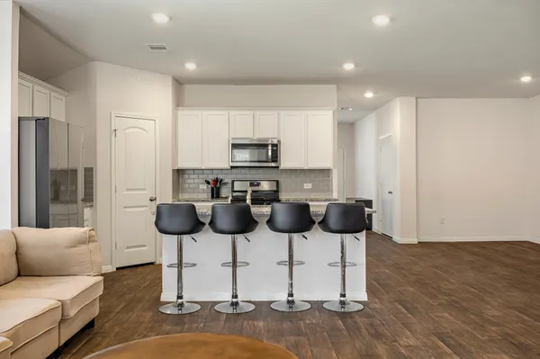 a kitchen with stainless steel appliances kitchen island granite countertop a refrigerator and a stove top oven with wooden floor