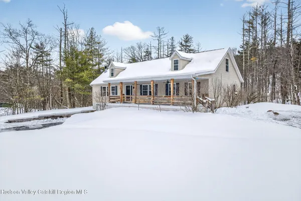 a front view of a house with a yard covered with snow and trees