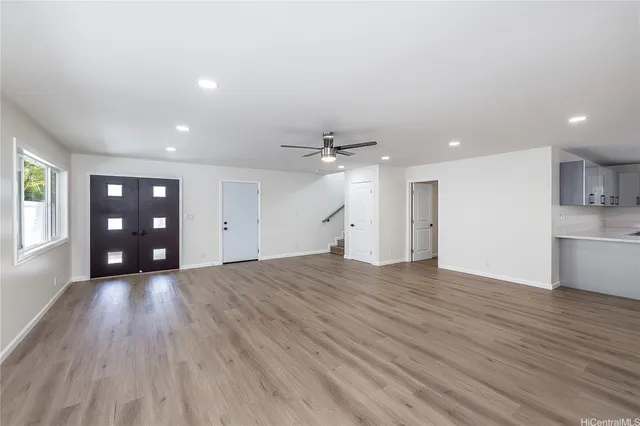 a view of an empty room with window and wooden floor