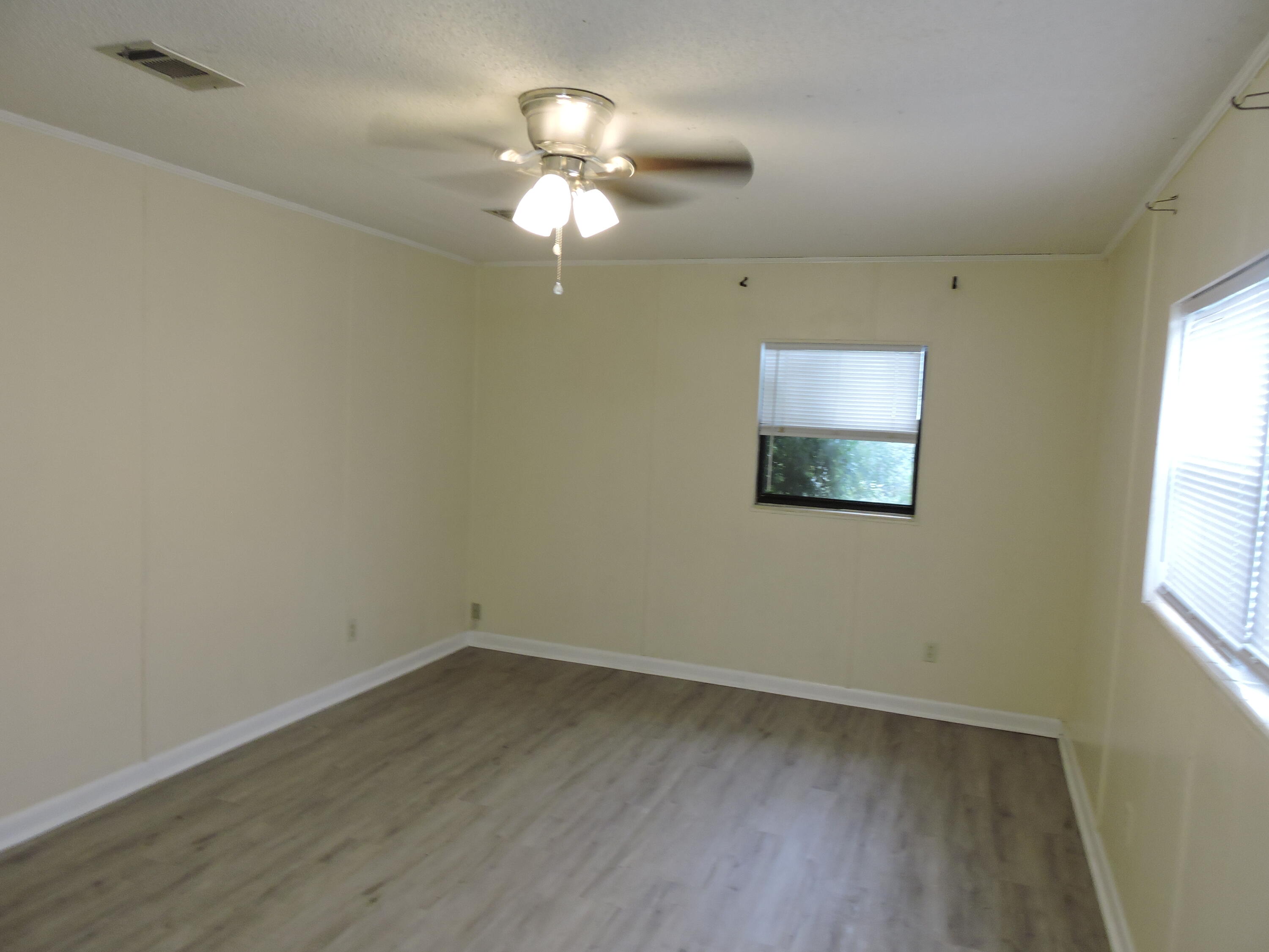 120 Sikes Drive Crestview, FL 32539 - Photo 4 of 18 wooden floor in an empty room with a window