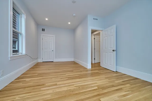 a view of empty room with wooden floor and entryway