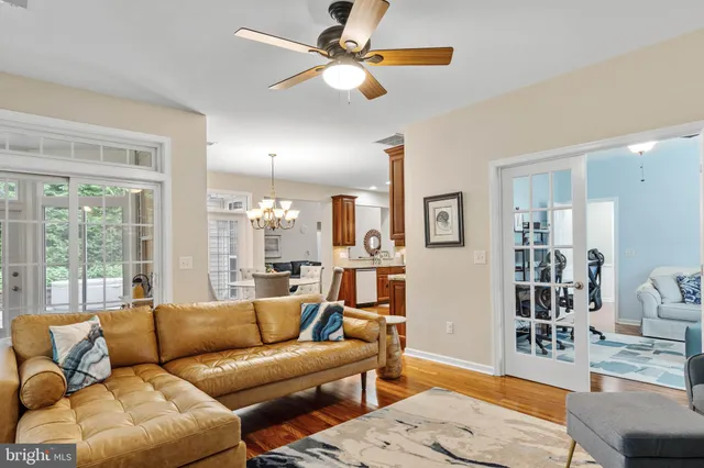 a living room with furniture a chandelier fan and a large window