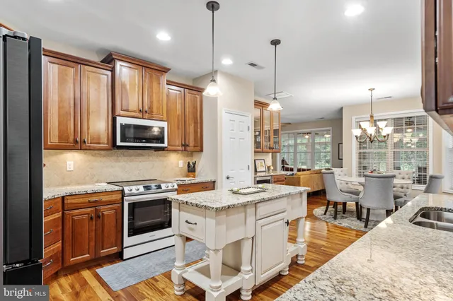 a large kitchen with stainless steel appliances granite countertop a stove a sink dishwasher a dining table and chairs with wooden floor