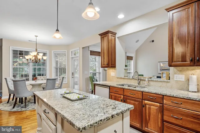 a kitchen with granite countertop kitchen island stainless steel appliances a sink stove and cabinets
