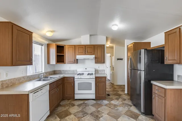 a kitchen with stainless steel appliances granite countertop a sink stove refrigerator and cabinets