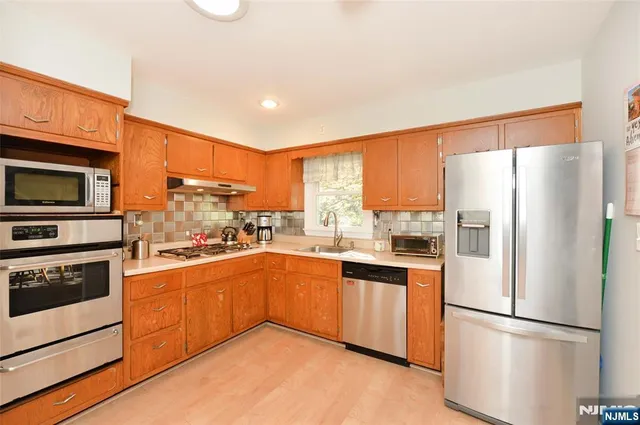 a kitchen with stainless steel appliances granite countertop a refrigerator a stove top oven a sink and dishwasher