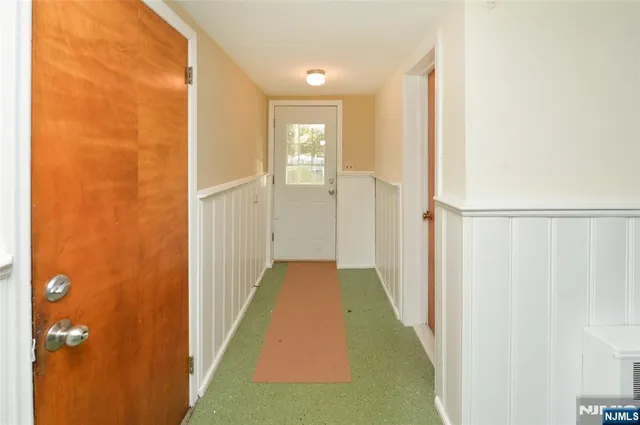 a view of a hallway with wooden floor and a bathroom