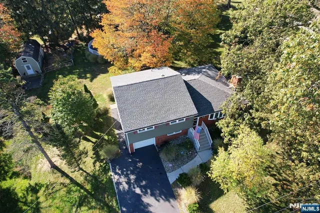 an aerial view of a house with yard and trees all around