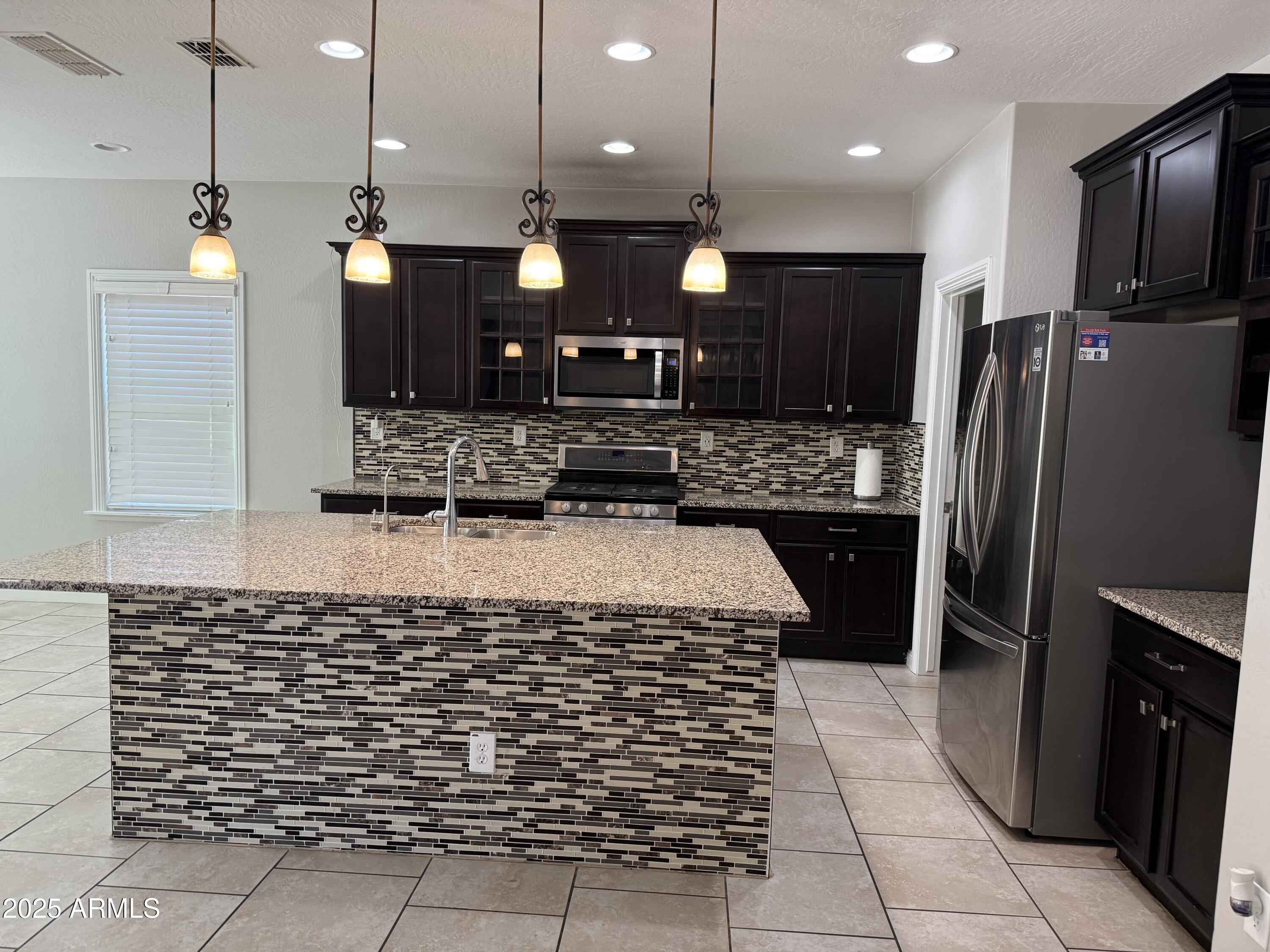 1843 West Fetlock Trail Phoenix, AZ 85085 - Photo 3 of 36 a kitchen with kitchen island a counter top space a sink appliances and cabinets