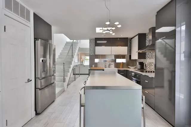 a kitchen with stainless steel appliances granite countertop a refrigerator a sink dishwasher a oven and a refrigerator with wooden floor