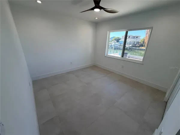 en empty room with windows and ceiling fan