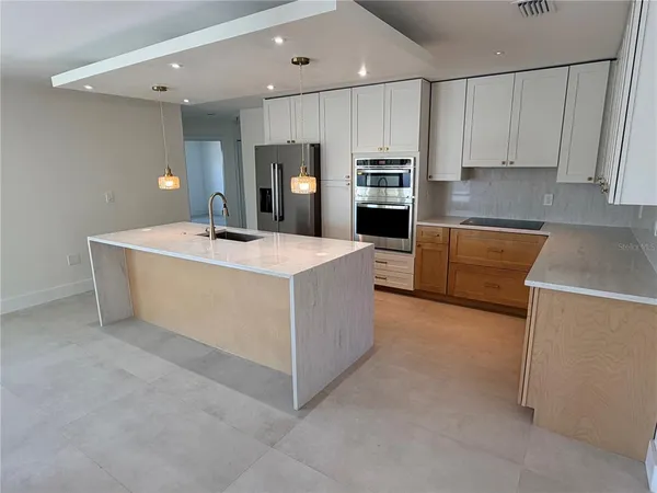 a large kitchen with stainless steel appliances a sink a stove a refrigerator a microwave and cabinets