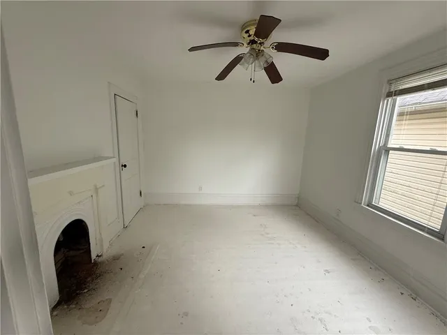 a view of a livingroom with a fireplace a ceiling fan and window