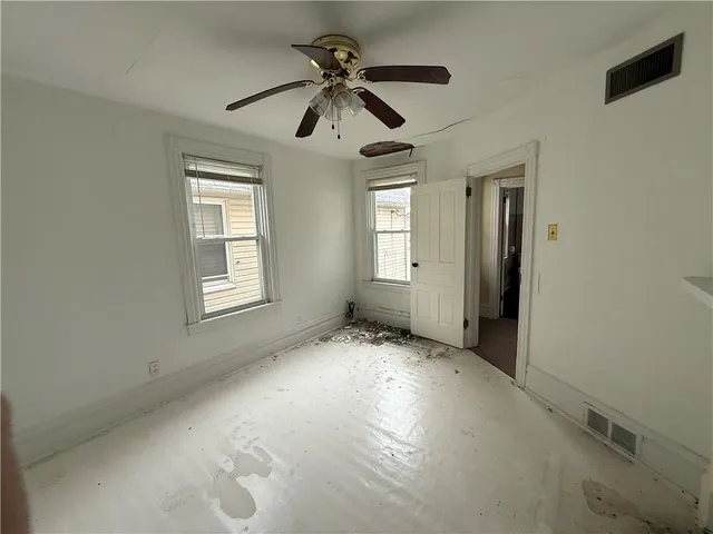 an empty room with windows and fan