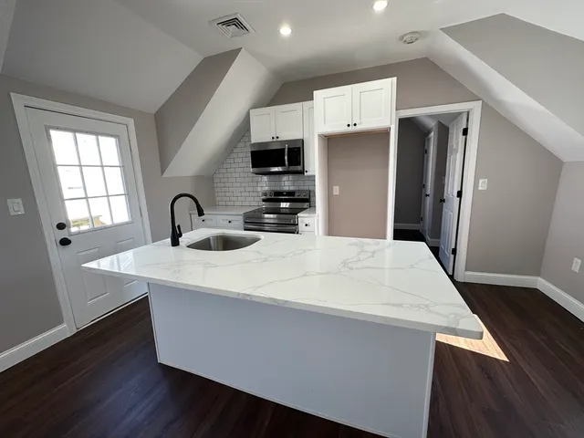 a kitchen with kitchen island a sink a stove a refrigerator and wooden floor
