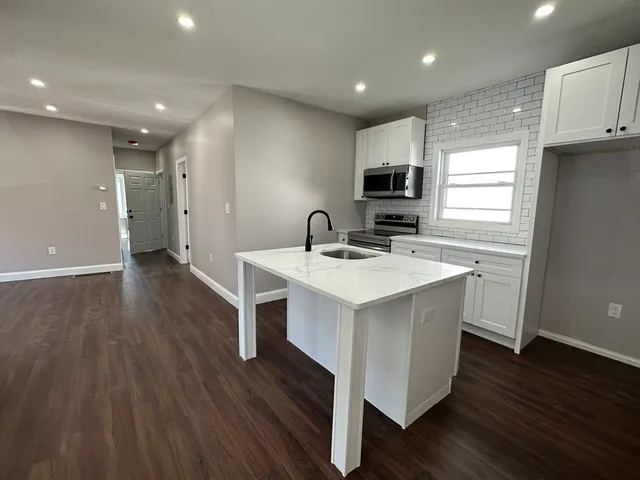 a kitchen with a sink cabinets and wooden floor