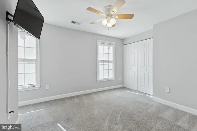 an empty room with windows and chandelier fan
