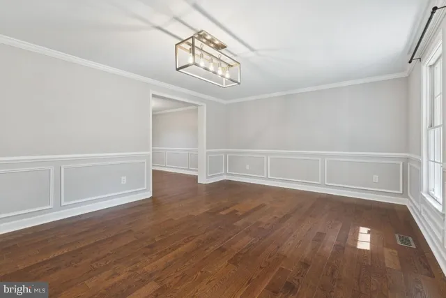 an empty room with wooden floor closet and windows