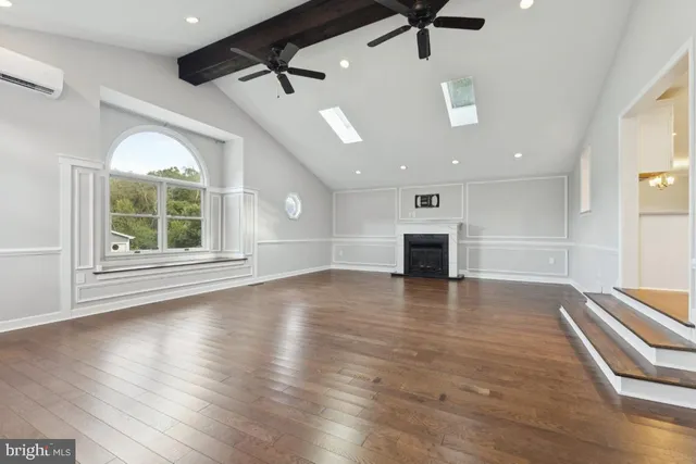 an empty room with wooden floor fireplace and windows
