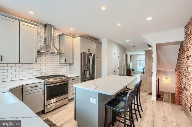 a kitchen with stainless steel appliances kitchen island granite countertop a stove a refrigerator a oven a sink with a dining table and chairs