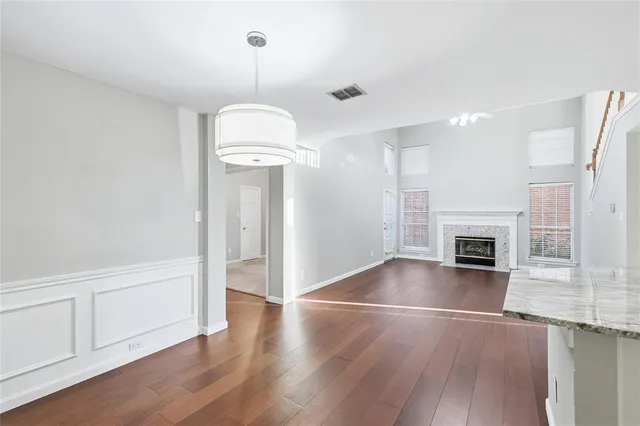 an empty room with wooden floor fireplace and windows