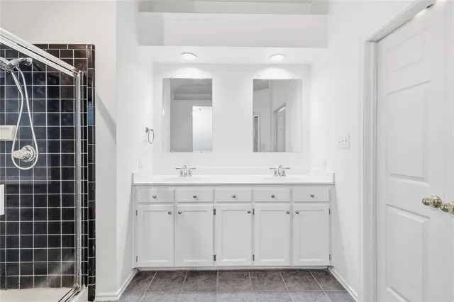 a bathroom with a double vanity sink a large mirror a shower and