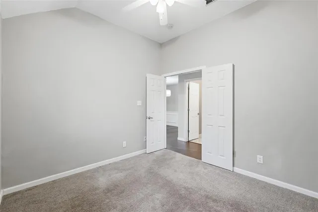 a view of an empty room and chandelier fan