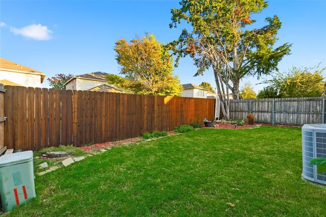 a view of a backyard with large trees and wooden fence