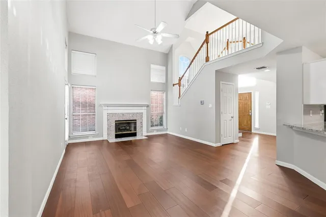 a view of an empty room with wooden floor fireplace and a window