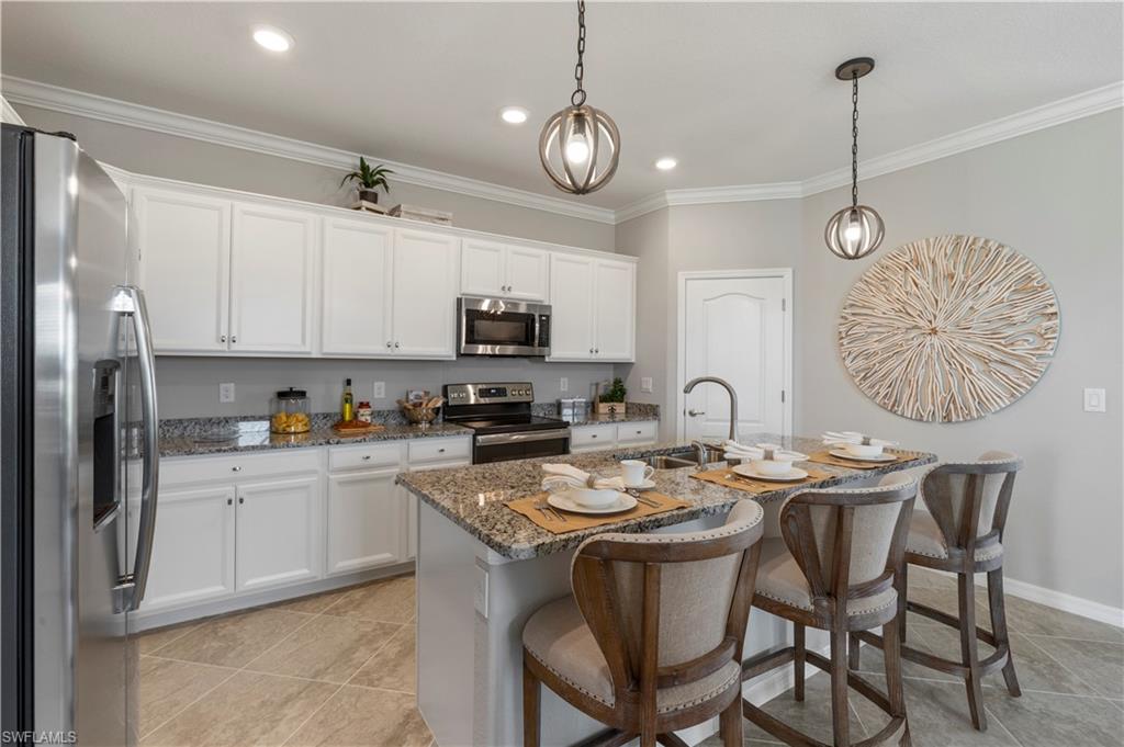 16100 Bonita Landing Circle Bonita Springs, FL 34135 - Photo 7 of 28 a kitchen with stainless steel appliances granite countertop a stove a sink a dining table and chairs