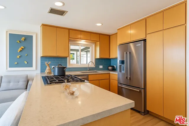 a kitchen with stainless steel appliances granite countertop a refrigerator a stove and a sink with wooden floor