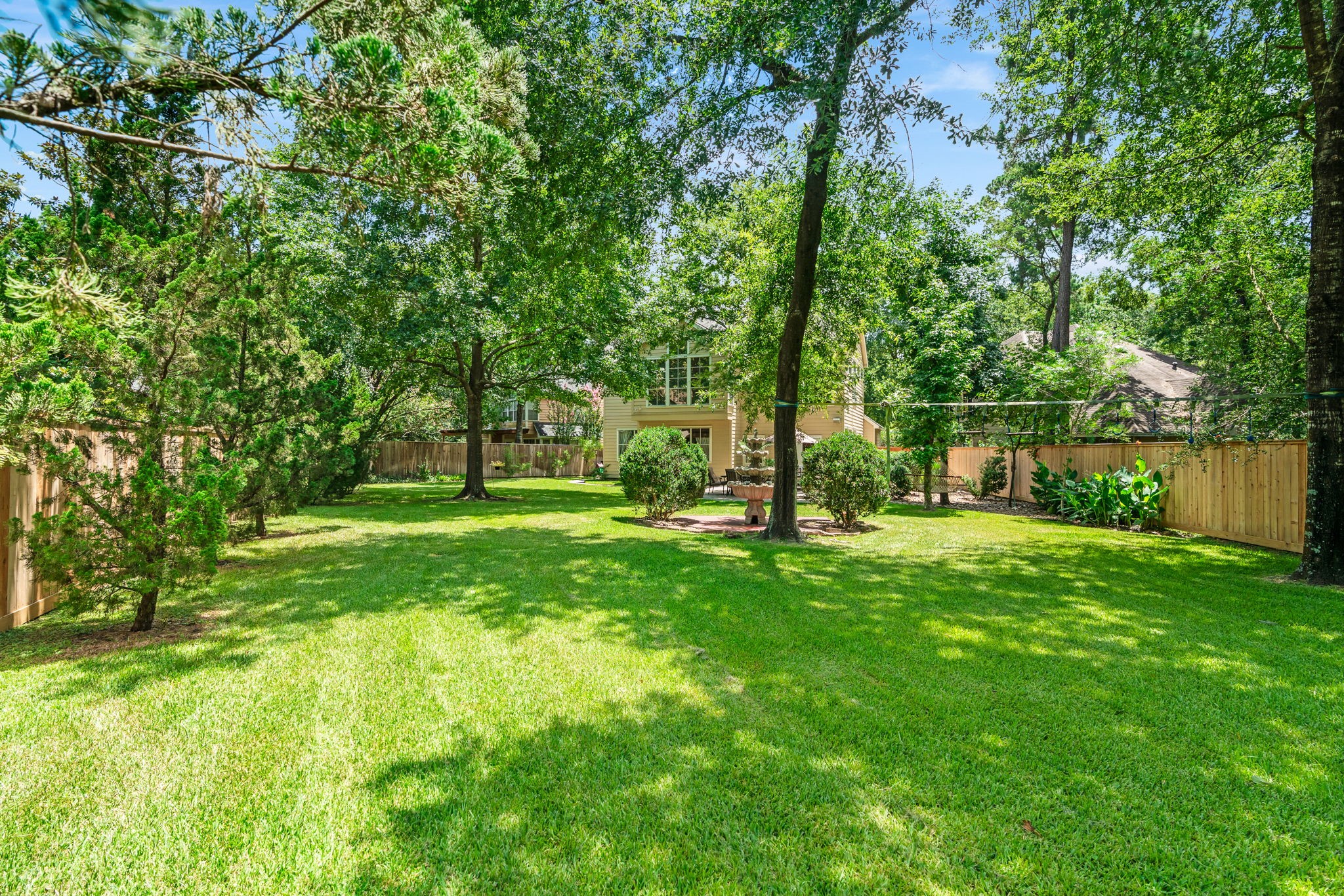 11 Dovewing Place Spring, TX 77382 - Photo 26 of 32 Spacious backyard with lush green lawn, mature trees, and a cozy patio area, offering plenty of privacy and room for outdoor activities.