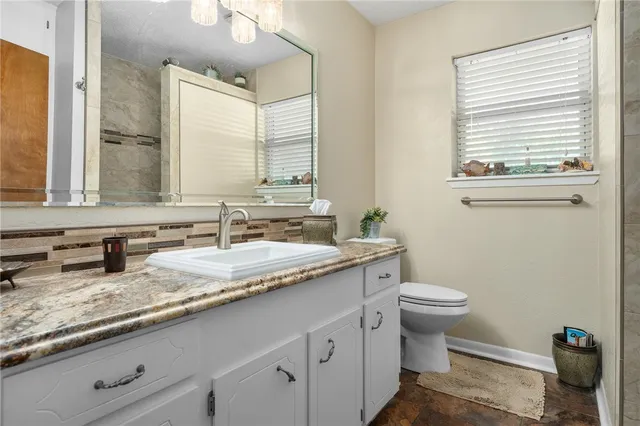 a bathroom with a granite countertop toilet sink and mirror