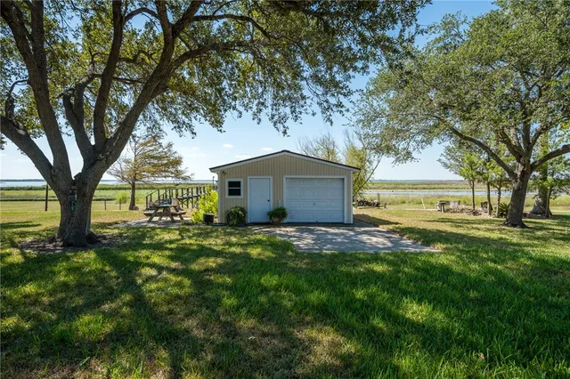 a backyard of a house with table and chairs under an umbrella