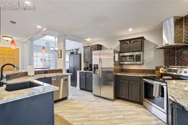 a kitchen with stainless steel appliances granite countertop a sink stove and refrigerator