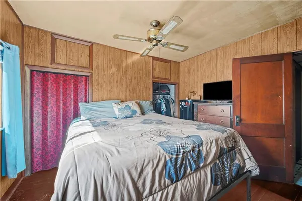a bedroom with a bed wooden floor and flat screen tv