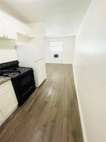 a view of a kitchen with wooden floor and electronic appliances