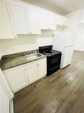 a kitchen with granite countertop white cabinets and white appliances