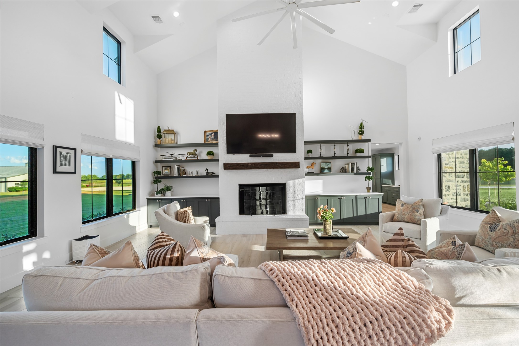 24118 Margerstadt Road Hockley, TX 77447 - Photo 14 of 50 Statement fireplace anchors the living room with built-in shelving and cabinetry on both sides, while soaring ceilings and windows frame the pastoral landscape. Staged for your convenience as the house is currently vacant.