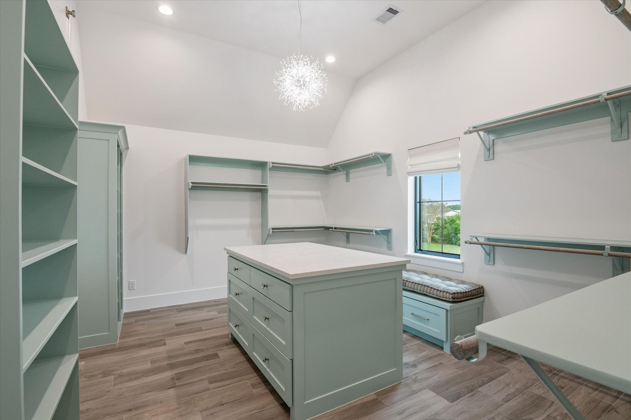 24118 Margerstadt Road Hockley, TX 77447 - Photo 22 of 50 Spacious, thoughtfully designed walk-in closet featuring custom built-ins, a large center island with drawers, and dedicated hanging space for effortless organization. Tall ceilings, abundant lighting, and a window with views create a bright, functional retreat.