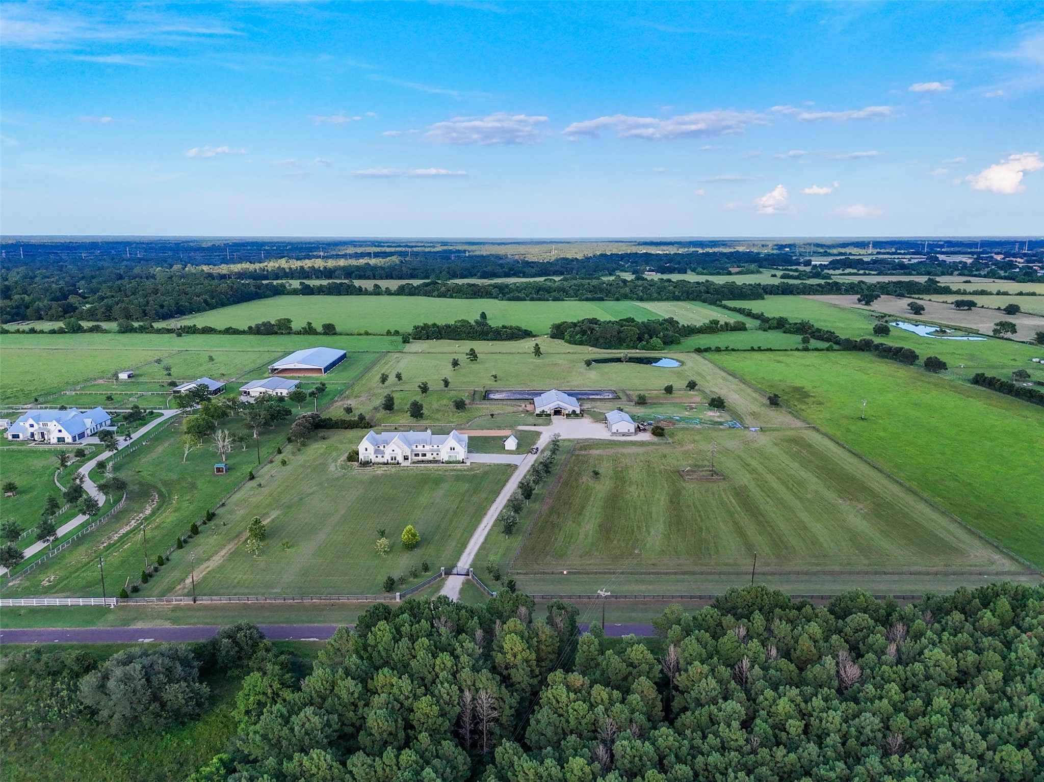 24118 Margerstadt Road Hockley, TX 77447 - Photo 49 of 50 Expansive aerial view highlights the fully fenced and cross-fenced +/- 19-acre estate, featuring the main home, barn, shop, dressage arena, and lush irrigated pastures laid out with engineered drainage.