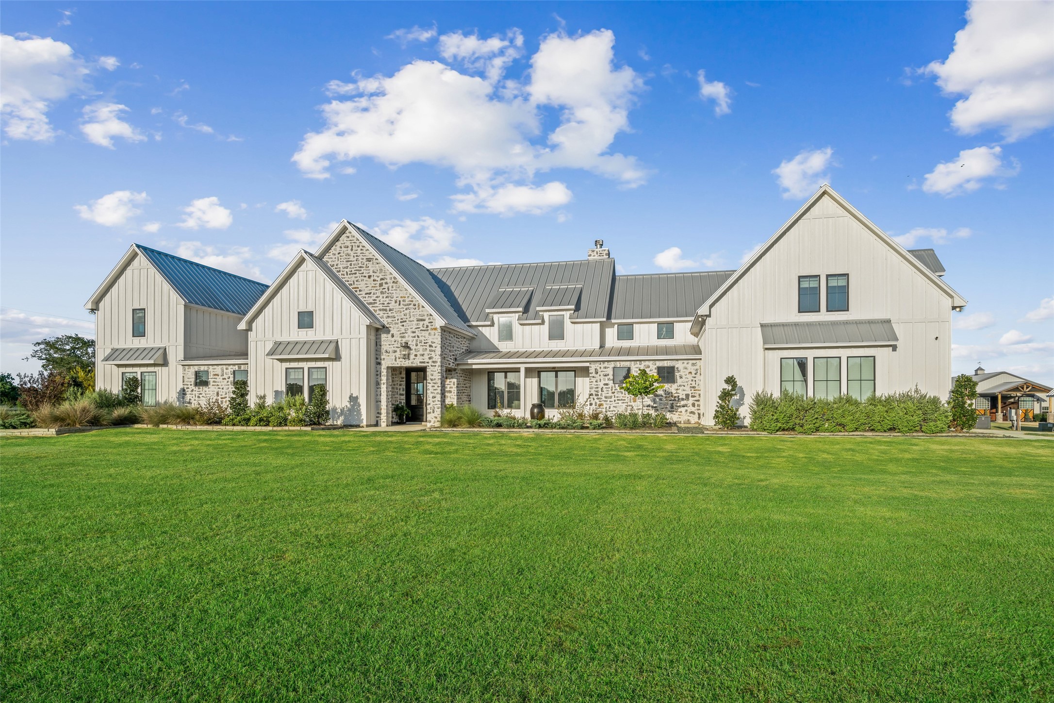 24118 Margerstadt Road Hockley, TX 77447 - Photo 8 of 50 Daylight also captures the architectural elegance of the main residence, with stone accents, Pella windows, and manicured landscaping stretching across the front lawn.