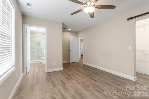 an empty room with wooden floor fan and windows