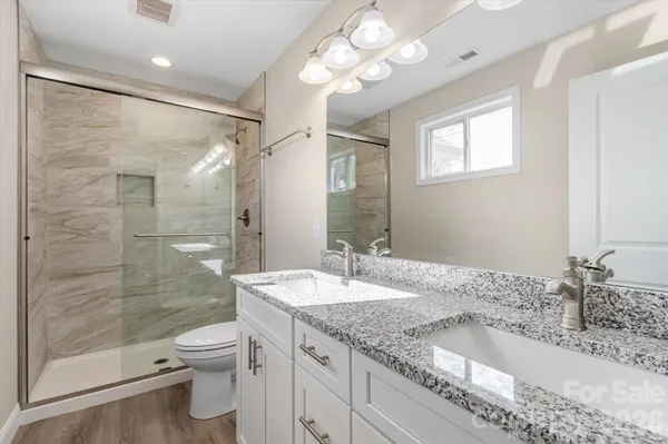 a bathroom with a granite countertop sink a toilet and shower
