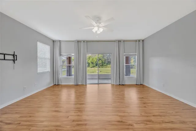a view of an empty room with a window and wooden floor