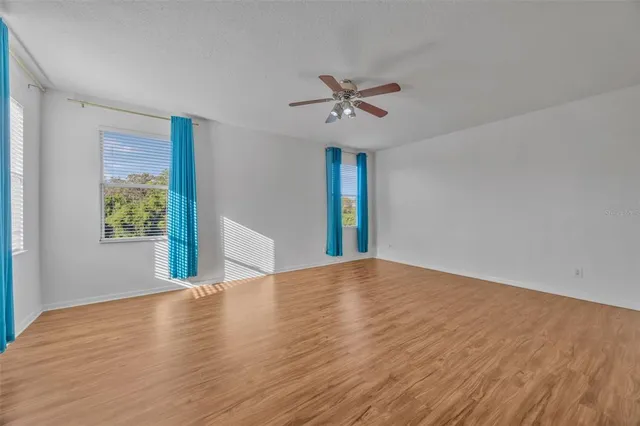 a view of empty room with wooden floor and fan