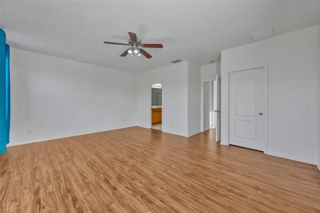 a view of empty room with wooden floor and ceiling fan