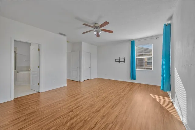 a view of empty room with wooden floor and ceiling fan