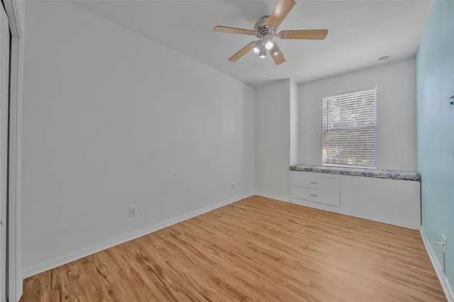 a view of empty room with wooden floor and fan