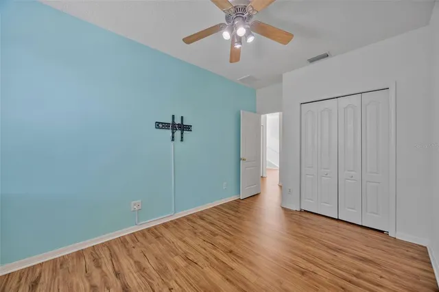 an empty room with wooden floor chandelier fan and closet area